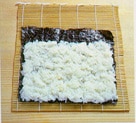 The sushi rice spread on the nori
